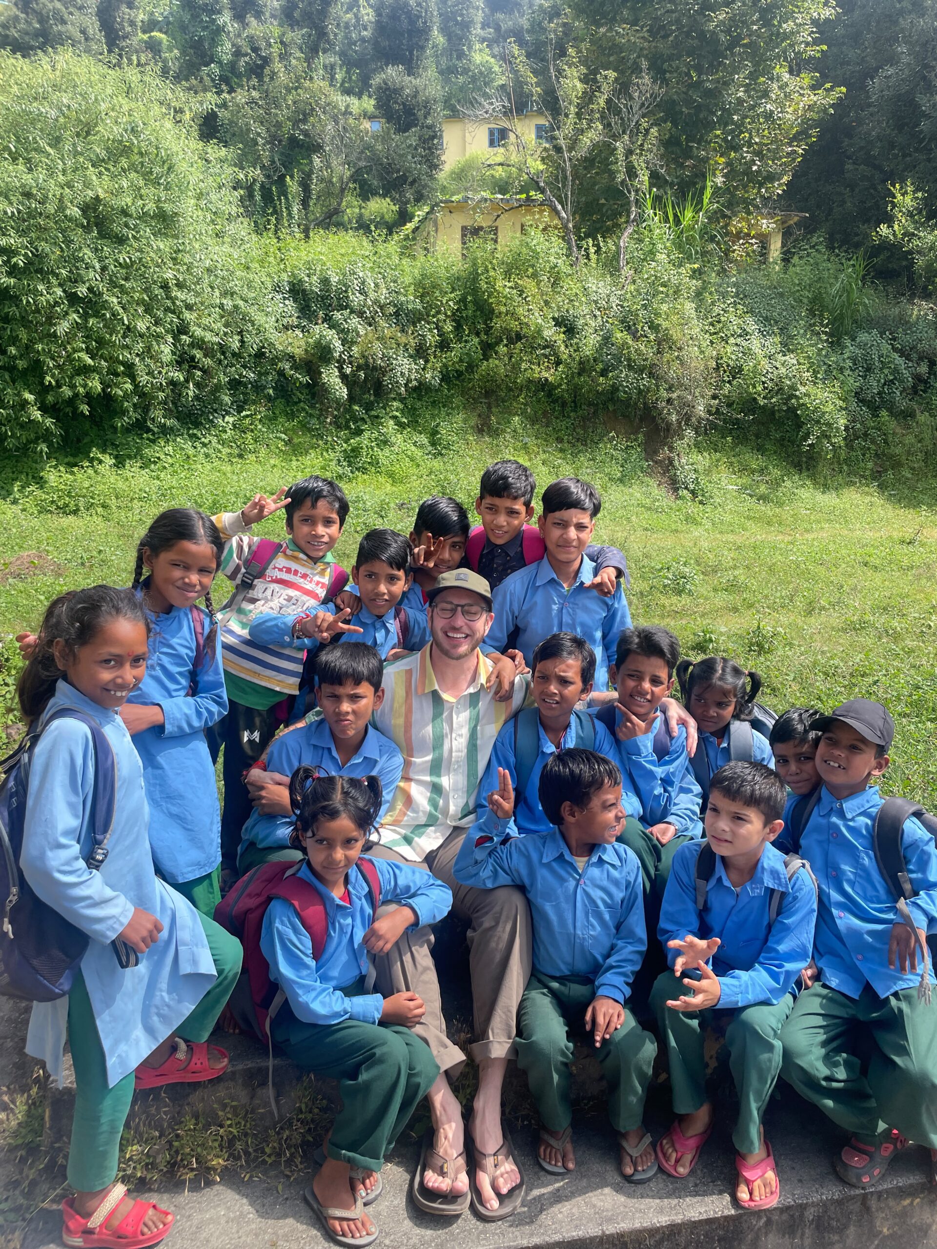 Children gathered outside on the grass with the hills behind them