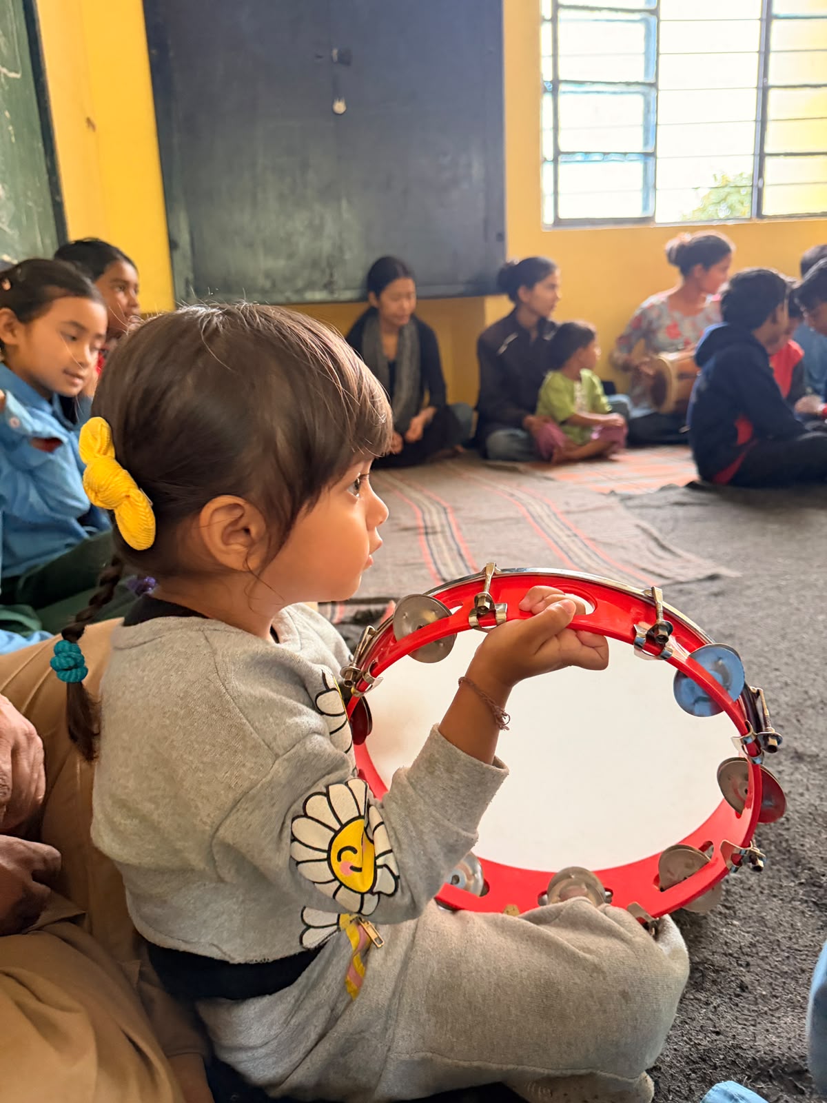 A child holding a painted tambourine during music class